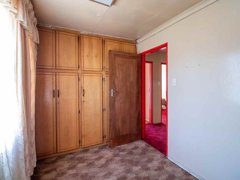 A bedroom featuring built-in wooden cupboards and carpeted flooring, offering a functional space ready for modernization and cosmetic updates.
