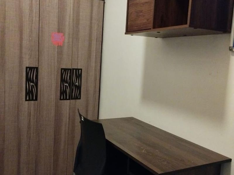 A bedroom featuring a built-in wardrobe with decorative detailing, a wall-mounted storage unit, and tiled flooring.