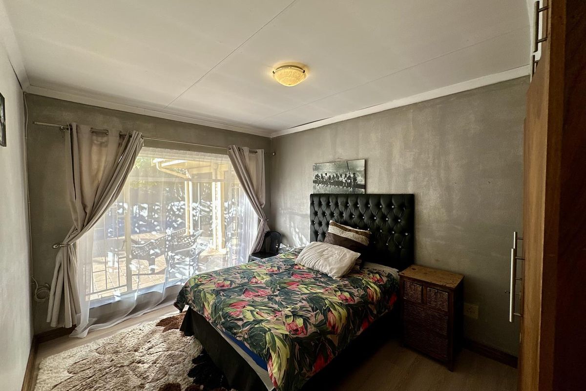 A bedroom featuring a built-in wardrobe, laminate flooring, and a sliding glass door providing access to an outdoor patio area.