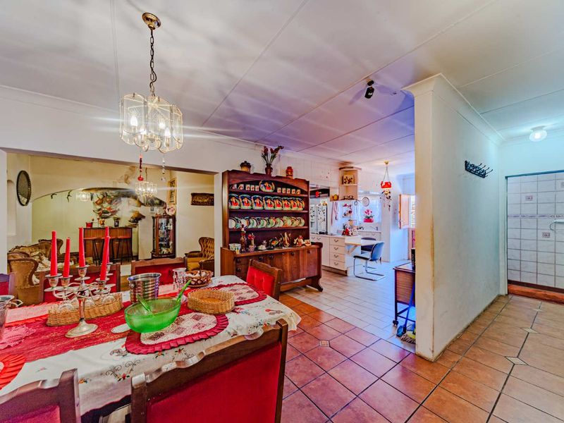 Open-plan living and dining area featuring tiled flooring, coved ceilings, and a connected kitchen space with built-in cabinetry.