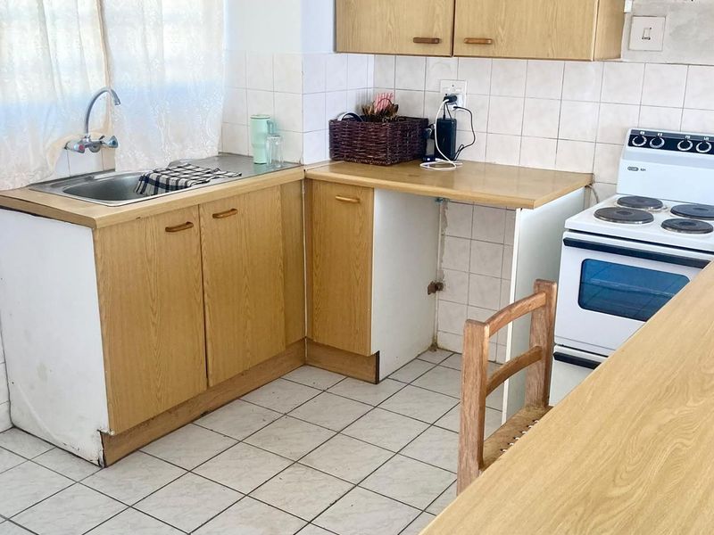 A dated kitchen featuring laminate cabinetry, tiled backsplash, and a freestanding stove, offering potential for a modern renovation.