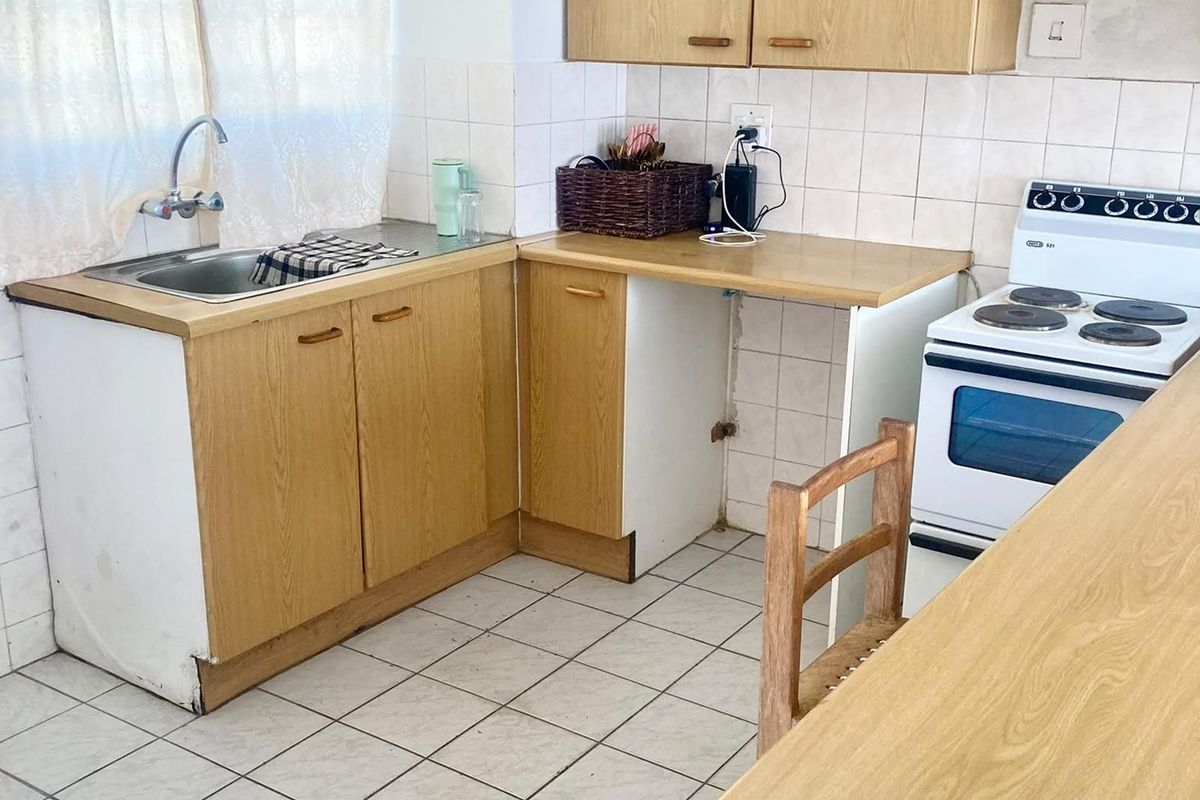 A dated kitchen featuring laminate cabinetry, tiled backsplash, and a freestanding stove, offering potential for a modern renovation.