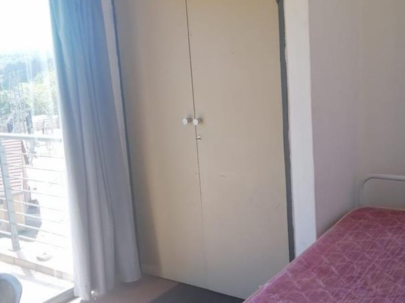 A bedroom featuring a built-in wardrobe and sliding glass door access to a balcony, providing natural light and outdoor connectivity.