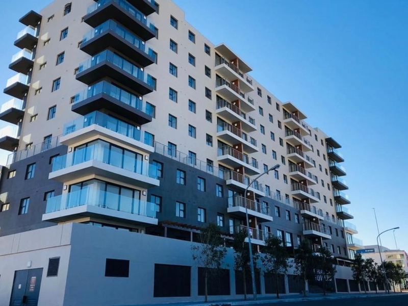 A modern multi-story apartment building featuring contemporary architecture with glass-fronted balconies and a clean, well-maintained exterior facade.