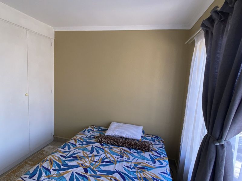 A bedroom featuring a built-in wardrobe and neutral wall finishes, offering a functional space with potential for cosmetic updates.