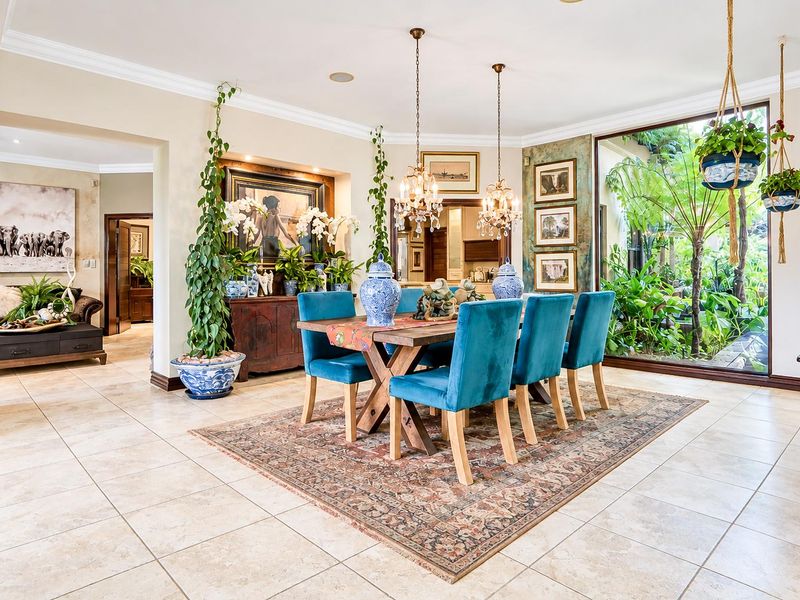 Elegant dining room featuring tiled flooring, crown molding, and a large picture window overlooking a lush garden, creating a bright and inviting atmosphere.