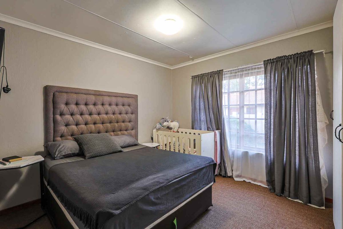 A standard bedroom featuring carpeted flooring, a window with curtain tracks, and a ceiling-mounted light fixture.