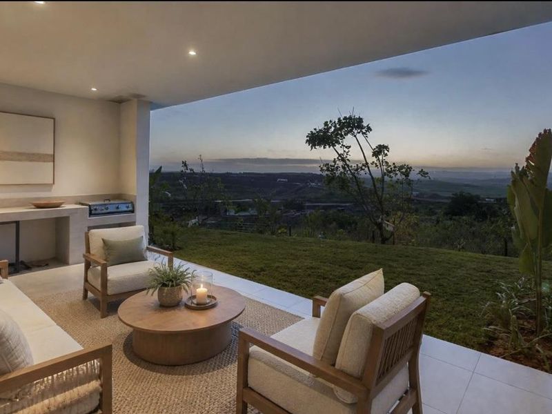 Covered patio featuring a built-in braai, recessed lighting, and tiled flooring, offering expansive views over the garden and surrounding landscape.