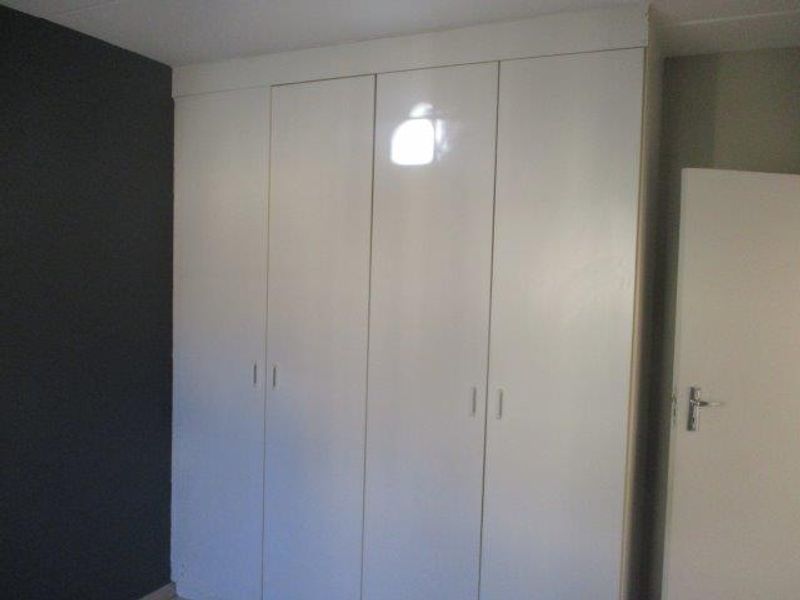 A bedroom featuring white built-in cupboards with a dark accent wall.