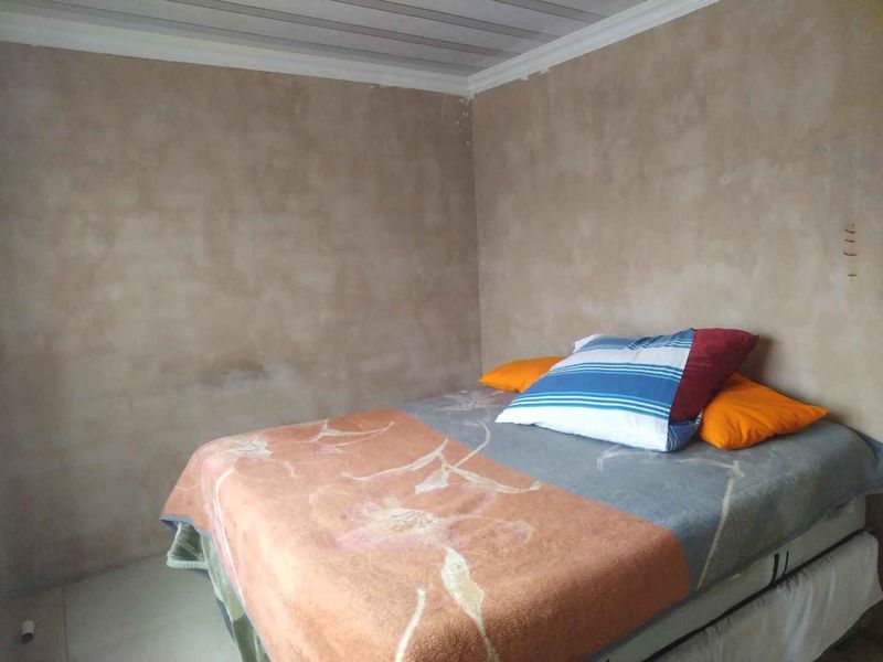 A bedroom featuring tiled flooring and a coved ceiling, currently requiring wall finishing and painting to complete the space.