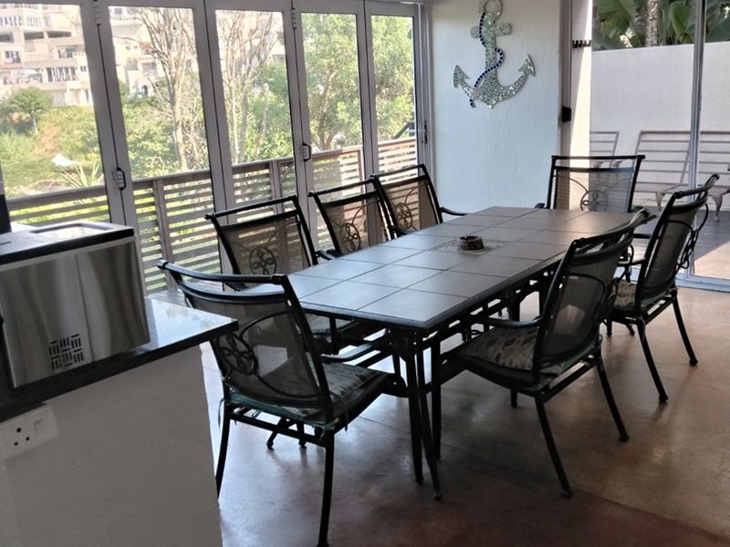 A covered patio area featuring bi-fold glass doors, recessed lighting, and concrete flooring, offering a seamless transition to outdoor living space.