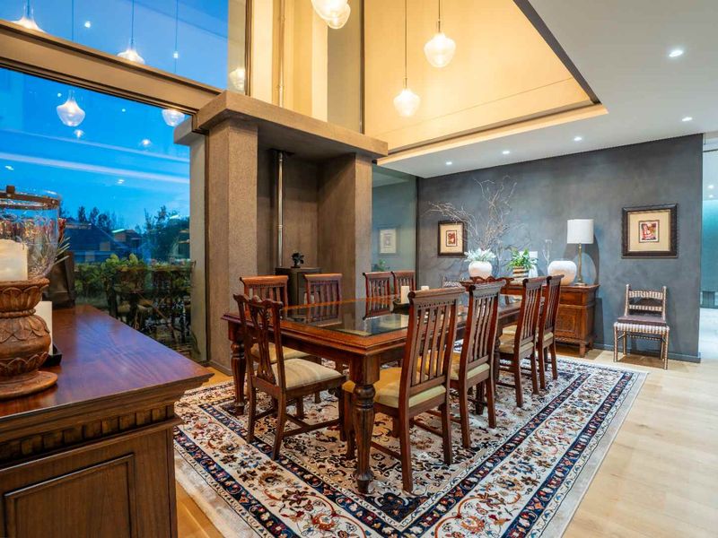Elegant dining room featuring hardwood flooring, a prominent wood-burning fireplace, and expansive floor-to-ceiling windows that provide ample natural light.
