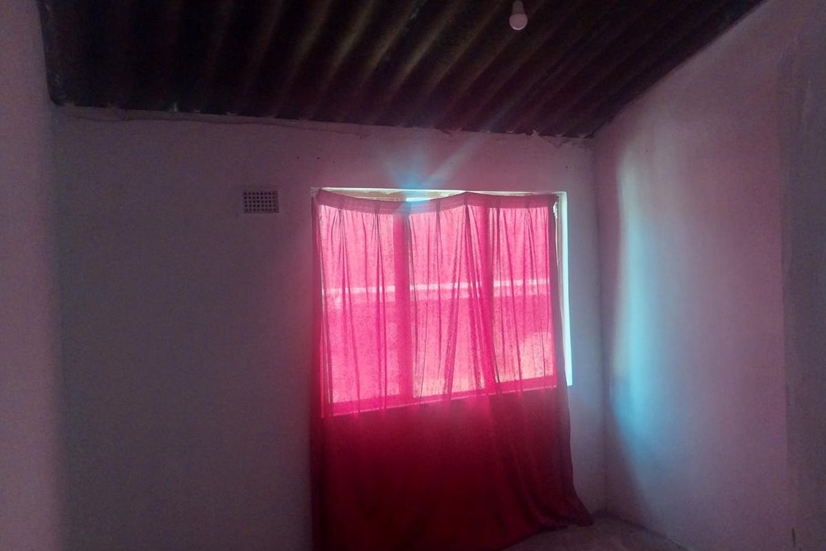 A basic, empty bedroom featuring a corrugated iron ceiling and a single ventilation brick, requiring significant cosmetic updates and finishing.