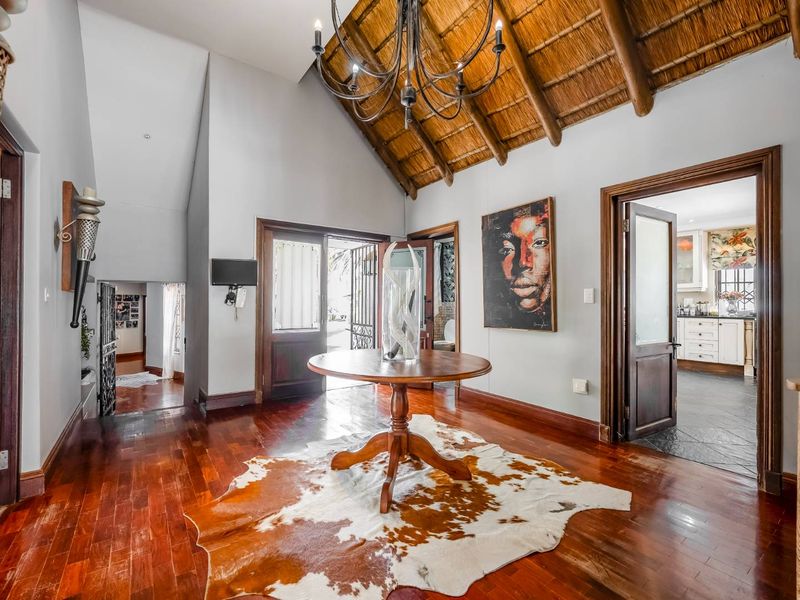 Spacious entrance hall featuring high vaulted ceilings with exposed thatch and timber rafters, complemented by rich hardwood flooring and elegant timber door frames.