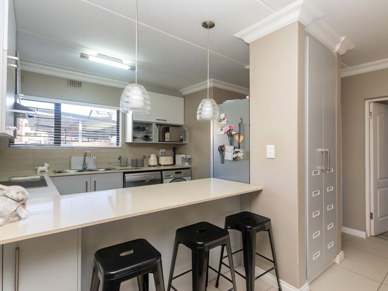 A functional kitchen featuring a breakfast bar, ample built-in cabinetry, a pantry, and tiled flooring, offering a clean and practical layout.