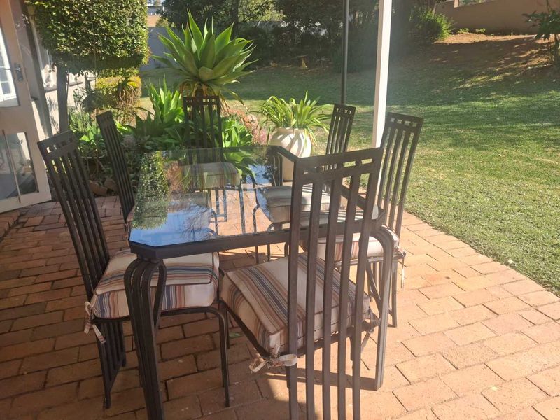 A covered outdoor patio area featuring brick paving, providing a pleasant space for alfresco dining overlooking the garden.