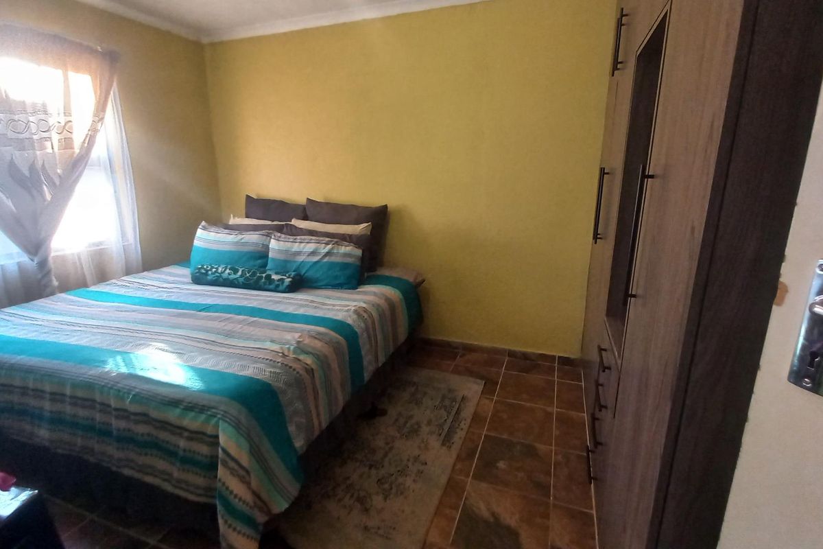 A bedroom featuring tiled flooring and a built-in wardrobe, providing functional storage space.