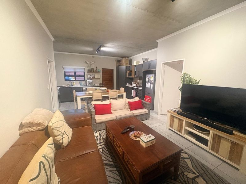 Open-plan living and kitchen area featuring tiled floors, coved ceilings, and modern dark-toned kitchen cabinetry.