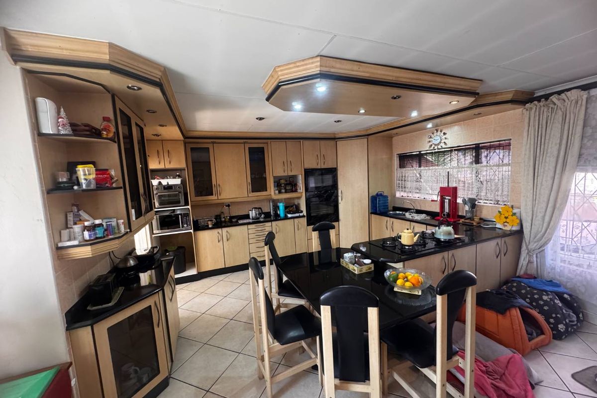 Spacious kitchen featuring extensive built-in cabinetry, granite countertops, integrated appliances, and a central breakfast nook with tiled flooring.