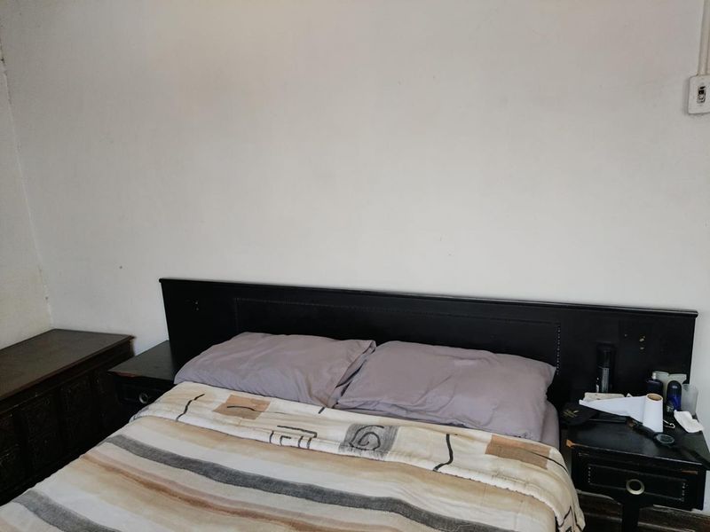 A bedroom featuring a built-in black headboard against a plain wall, providing a functional space for a double bed.