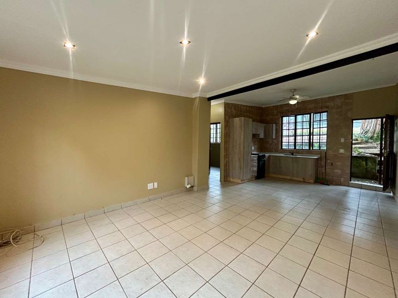 Open plan living and kitchen area featuring tiled floors, recessed lighting, and basic kitchen cabinetry with direct access to the exterior.