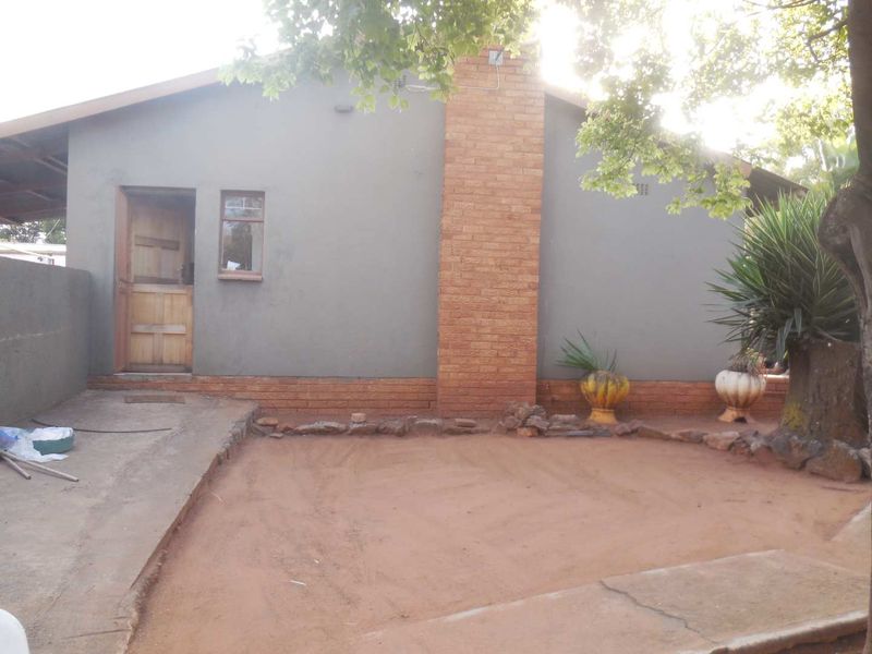 Rear exterior view of the house featuring a brick chimney, concrete patio area, and a timber door entrance.