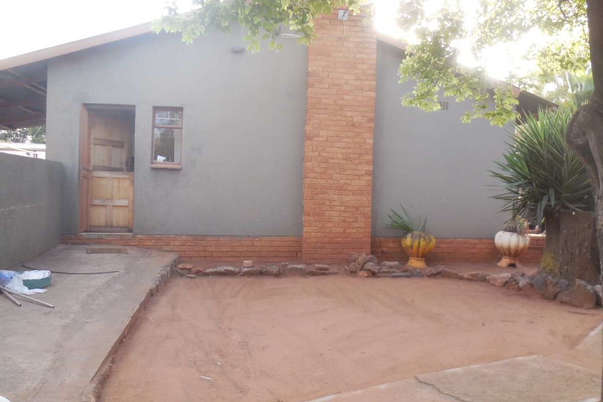 Rear exterior view of the house featuring a brick chimney, concrete patio area, and a timber door entrance.