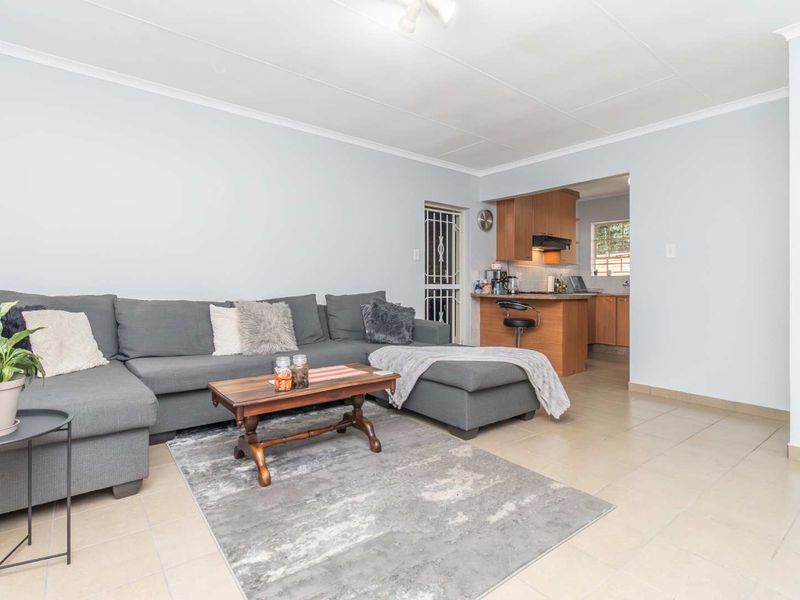 Open plan living area featuring tiled floors and a functional kitchen with wooden cabinetry and a breakfast bar.