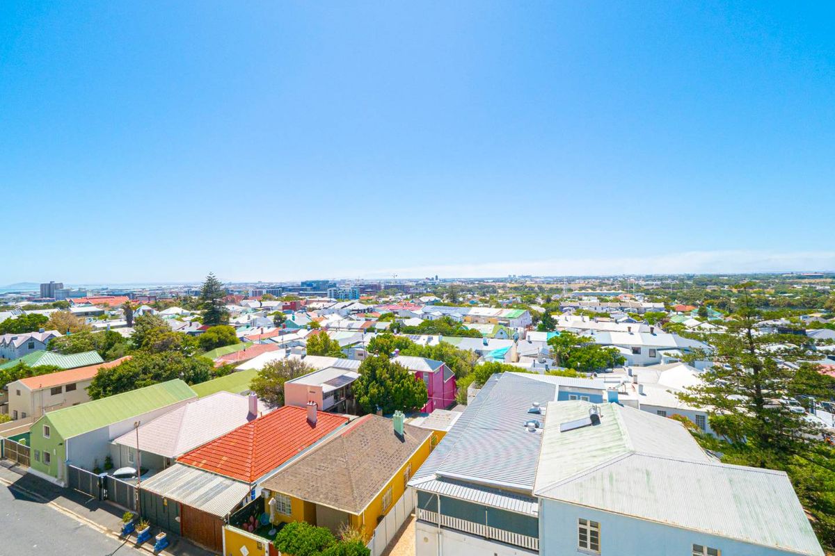 An elevated aerial view overlooking a residential neighborhood with various roof styles and urban landscape.