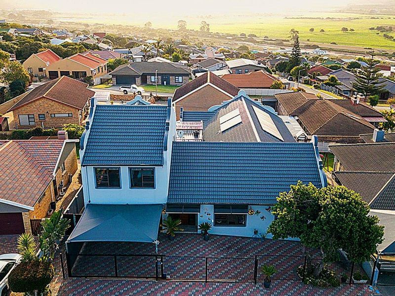 Aerial view of a residential property featuring a tiled roof with solar panels, a paved driveway, and a shade sail in a suburban setting.