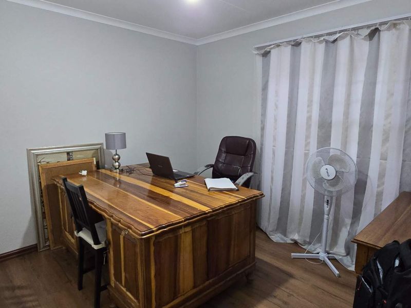 A functional home office space featuring laminate flooring and neutral wall finishes, suitable for a dedicated workspace or study area.