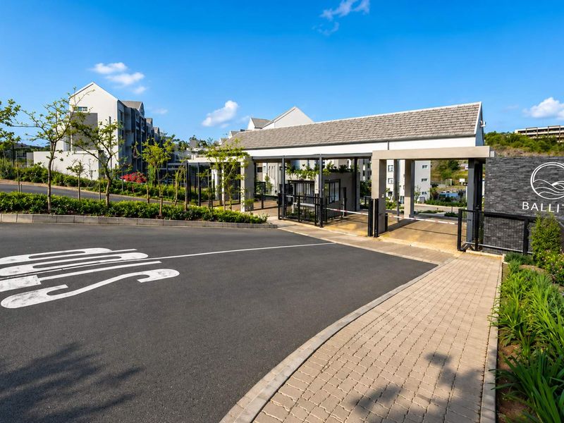 The entrance to the Ballito apartment complex features a modern security gatehouse, paved driveway, and professional landscaping, providing a secure and welcoming arrival.