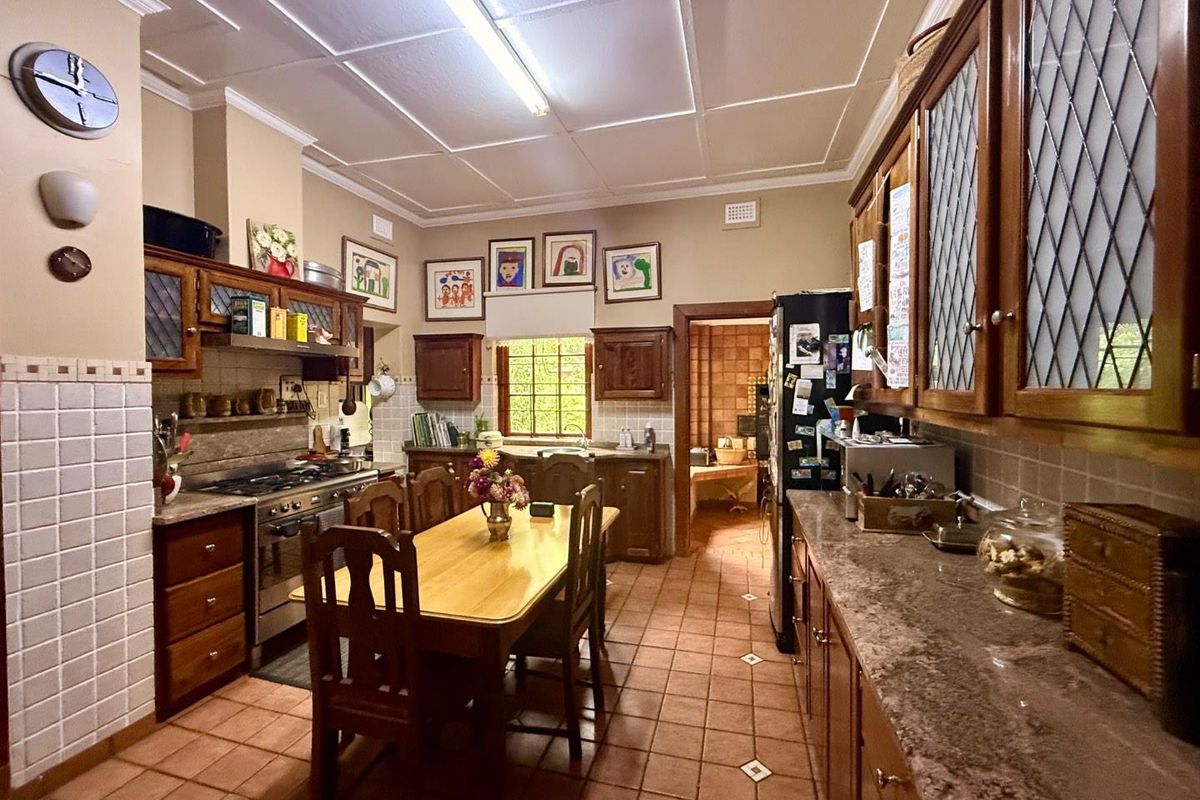A traditional kitchen featuring wooden cabinetry, tiled flooring, a built-in gas stove, and a dedicated dining area with a warm, classic aesthetic.