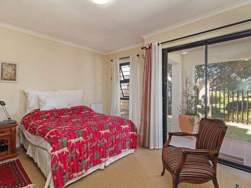 A bedroom featuring carpet flooring, a louver window, and a sliding glass door providing direct access to an outdoor patio area.
