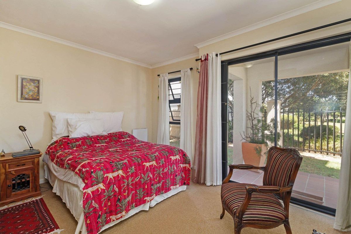 A bedroom featuring carpet flooring, a louver window, and a sliding glass door providing direct access to an outdoor patio area.