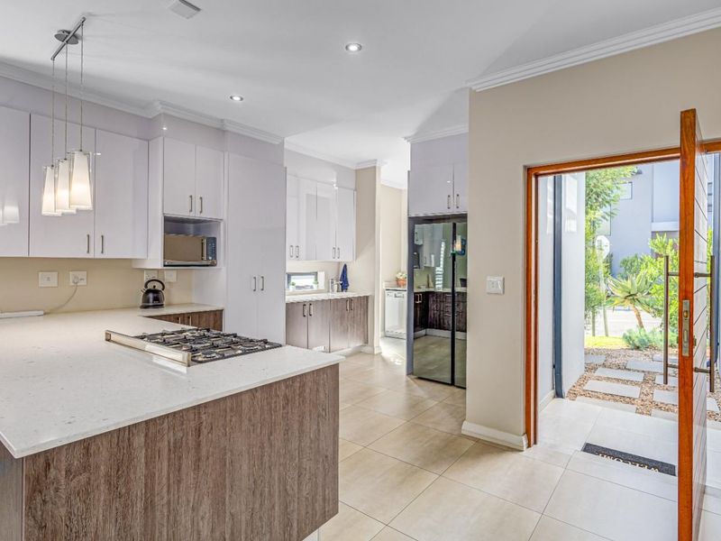 Modern kitchen featuring stone countertops, gas hob, built-in microwave, and sleek cabinetry, with direct access to an outdoor patio area.