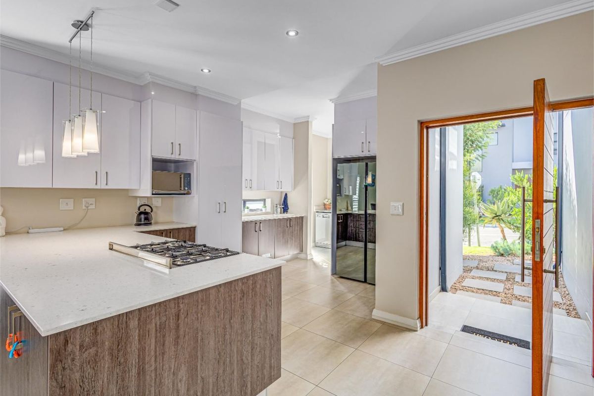 Modern kitchen featuring stone countertops, gas hob, built-in microwave, and sleek cabinetry, with direct access to an outdoor patio area.