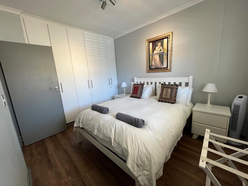 A well-maintained bedroom featuring laminate flooring, neutral walls, and extensive built-in cupboard storage.