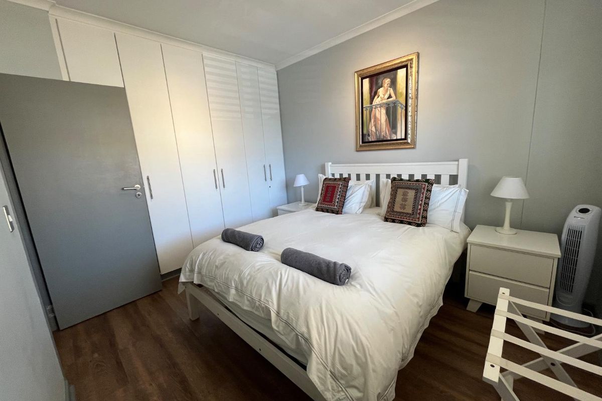 A well-maintained bedroom featuring laminate flooring, neutral walls, and extensive built-in cupboard storage.