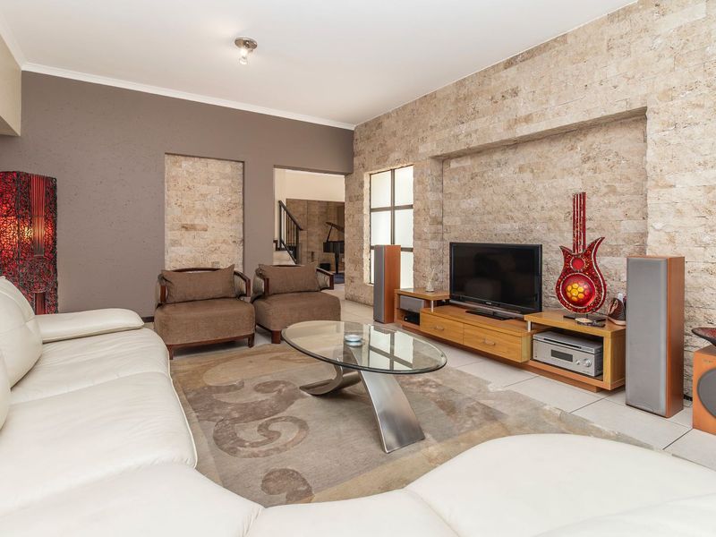 Spacious living room featuring a prominent natural stone feature wall, neutral tiled flooring, and a recessed wall niche.