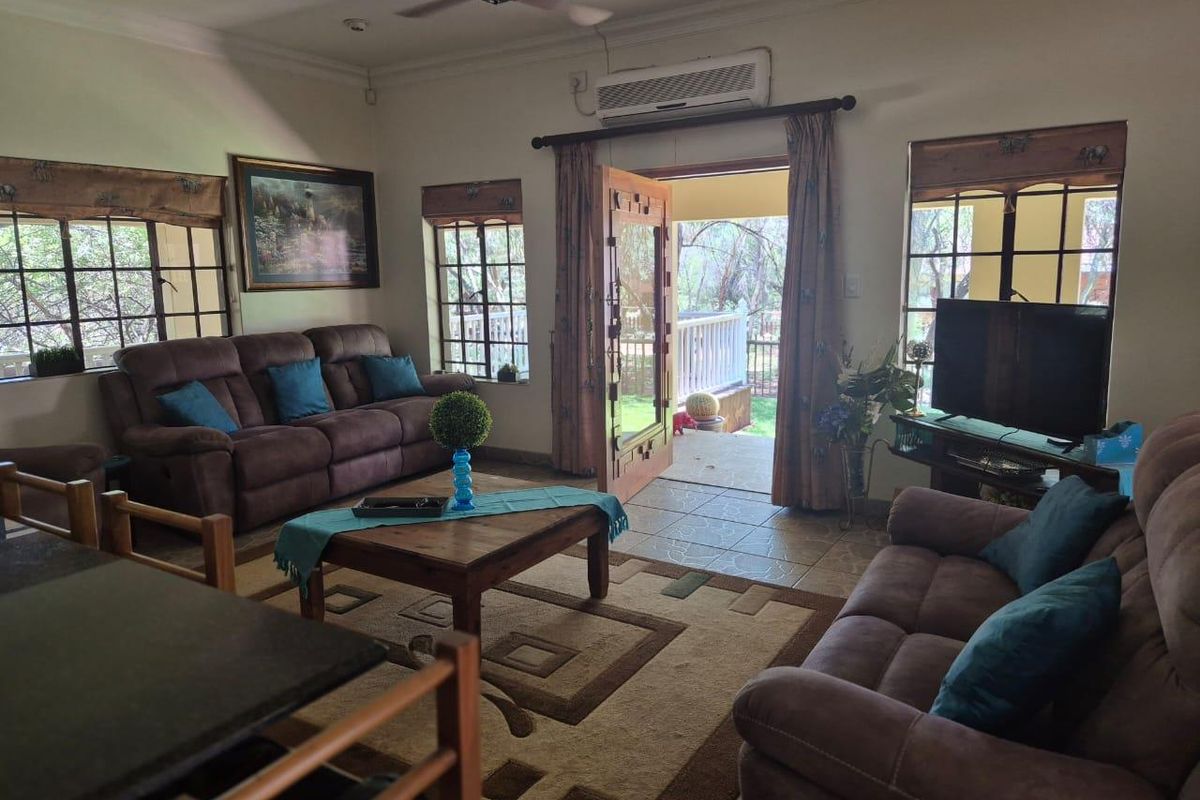 A comfortable living room featuring tiled flooring, a ceiling fan, wall-mounted air conditioning, and direct access to an outdoor patio area.