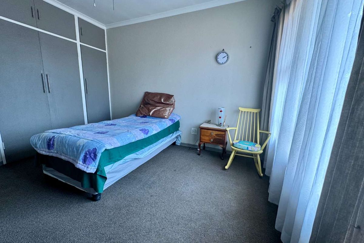 A functional bedroom featuring built-in cupboards, carpeted flooring, and large windows with curtain rails, offering a neutral base for personalization.