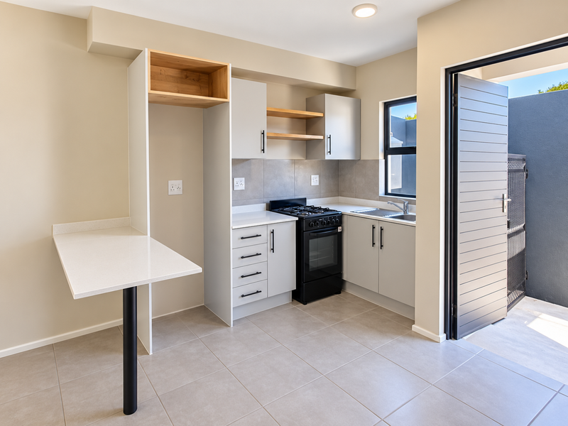 Modern kitchen featuring light grey cabinetry, stone countertops, a gas stove, and a breakfast bar, with direct access to an outdoor area.