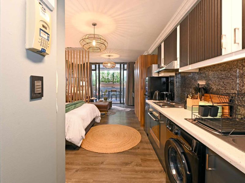 Modern open-plan apartment featuring a sleek kitchen with stone countertops, integrated appliances, and seamless flow to a private balcony area.