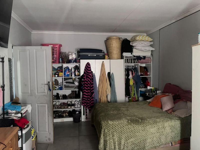 A bedroom featuring built-in storage cupboards, tiled flooring, and coved ceilings, offering a functional space with potential for cosmetic updates.
