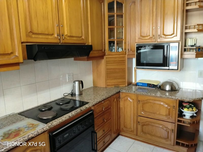 A functional kitchen featuring traditional wooden cabinetry, granite countertops, a built-in oven with hob, and an integrated microwave.