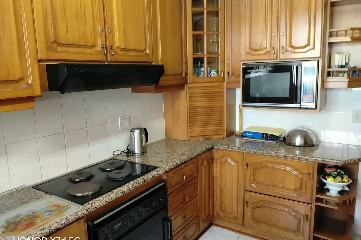 A functional kitchen featuring traditional wooden cabinetry, granite countertops, a built-in oven with hob, and an integrated microwave.
