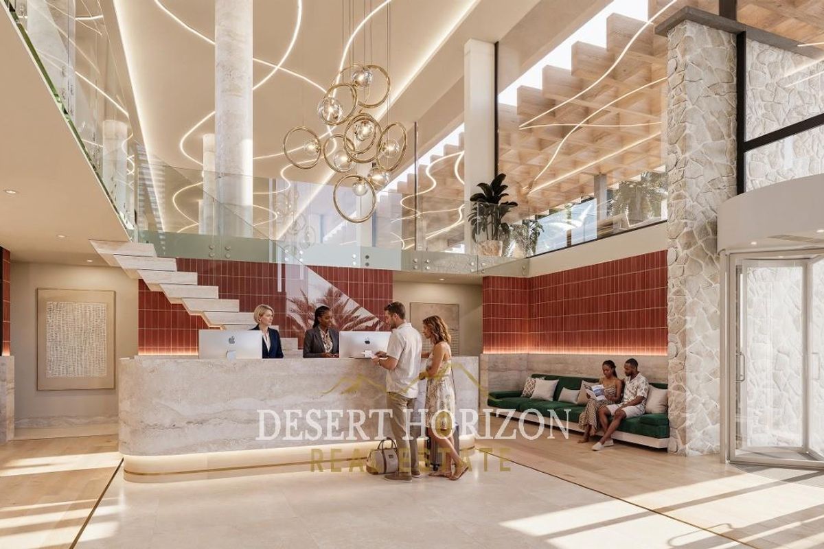 Modern hotel lobby featuring a stone reception desk, grand staircase with glass balustrade, and elegant architectural lighting in a spacious, high-ceilinged entrance area.