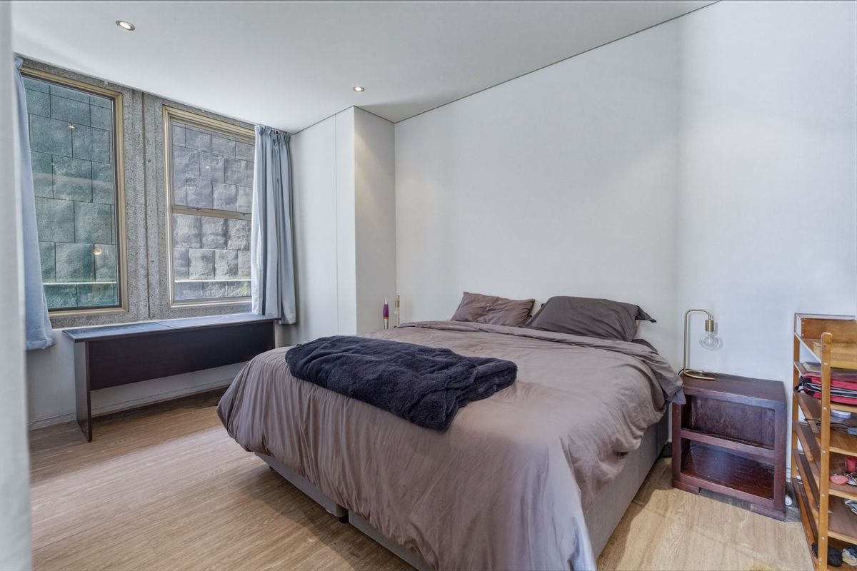 A well-lit bedroom featuring laminate flooring, recessed downlighting, and a built-in window ledge, offering a clean and functional living space.