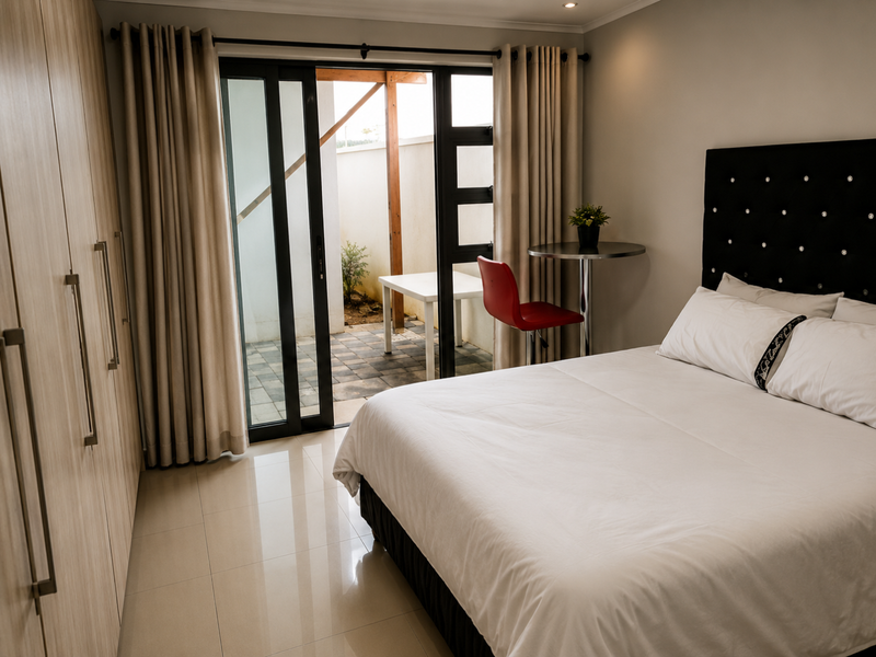A well-maintained bedroom featuring built-in cupboards, tiled flooring, and a sliding glass door providing direct access to a private patio area.